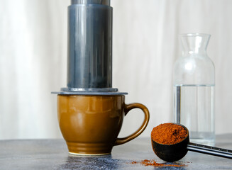 Aeropress coffee. Freshly brewed coffee in an Aeropress. Ground coffee in a measuring spoon.