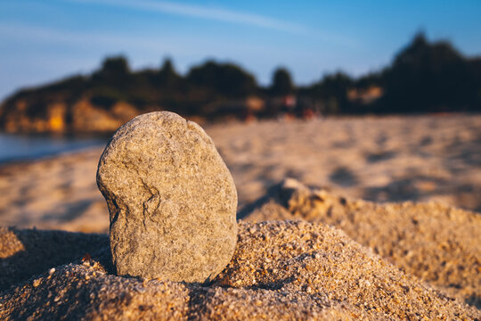 Stone wishes close up in the sand on the beach. Сlose up in sand stone on blurred sandy beach background.