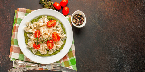 Paste with tomatoes and spinach sauce in a plate on a table. Selective focus. Copy space. Top view