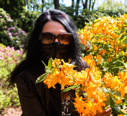 A girl in a mask and glasses smells yellow flowers. The concept of allergy and seasonal allergic...