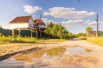 Street with a puddle and reflection of houses in the village