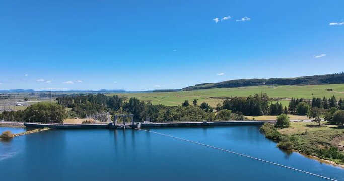 Aerial follows car pulling caravan over dam-top road - Whakamaru Dam NZ