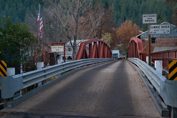 Bridge with road signs and the US flag in a small town of Downieville in CA, USA - obrazy, fototapety, plakaty