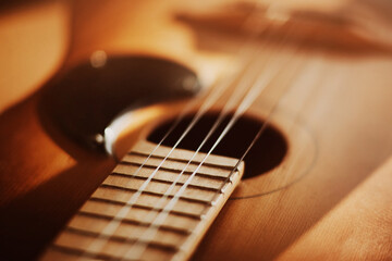 An old vintage acoustic guitar with metal strings is illuminated by sunlight. A musical instrument....