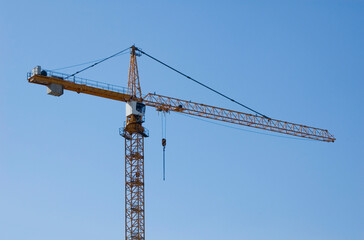Large construction site cranes working on a building complex with clear blue sky.