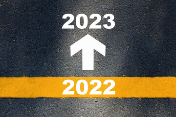 New year 2022 to 2023 and white arrow sign with yellow line marking on asphalt road. Business...