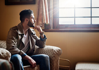 Thinking things through.... Shot of a handsome young man deep in thought while sitting on a chair...