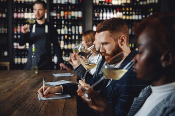Caucasian man and african woman sommelier bartender smelling white wine and making degustation card - obrazy, fototapety, plakaty