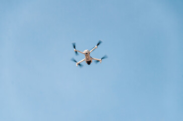 Drone flying in the air. Bottom view. Blue sky background. New technologies.