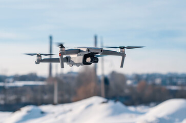 Modern gray drone in flight over the city. New technology. Blurred background.