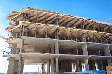 Concrete box of the building under construction. The skyscraper is built before the masonry walls and openings. Concrete columns and floors. Wooden fences and formwork.