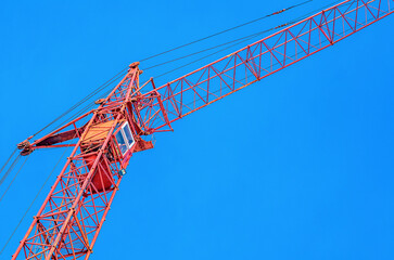 Construction crane on a background of blue sky. Crane driver's cab close up. Construction industry.