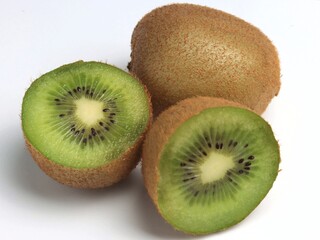 One whole kiwi and a second kiwi cut in half. Close-up, light gray background, selective focus.