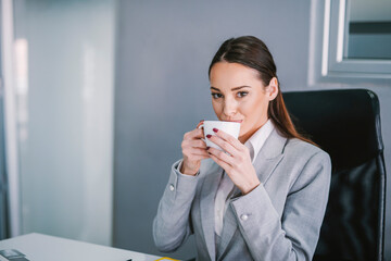 A businesswoman sipping coffee in modern office on coffee break.