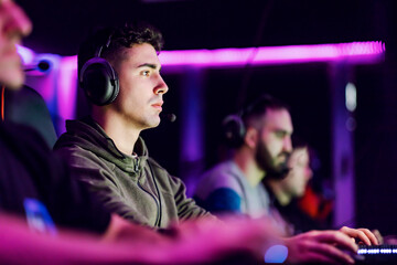 Gamer with his teammates playing video games at gaming room.