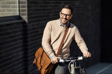 A laughing man pushing bicycle while walking outdoors.