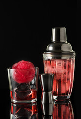 Red drink with ice and bar shaker, black background. Summer cold alcoholic soft drinks, drinks and cocktails.