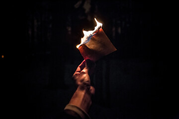 Close-up shot of a person holding a burning paper