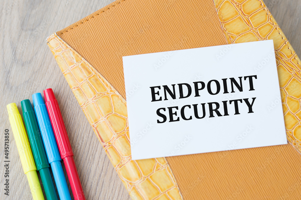 Poster text endpoint security on a card on a notebook on a wooden table next to colored markers