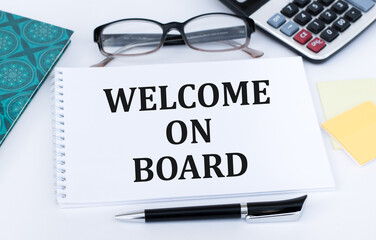 Welcome on board inscription on notepad on the table next to pen, calculator, glasses and documents