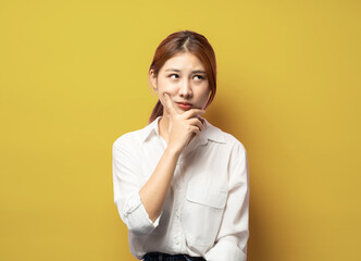 Indoor shot of thoughtful pretty woman has long  hair , looks aside with pensive expression, plans something on coming weekends, poses against blank wall. Puzzled female.