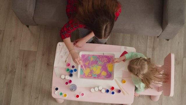 Mother teaches little daughter to draw patterns at Ebru art