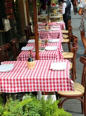 tables and chairs with red and white checkered tablecloths in an alfresco restaurant