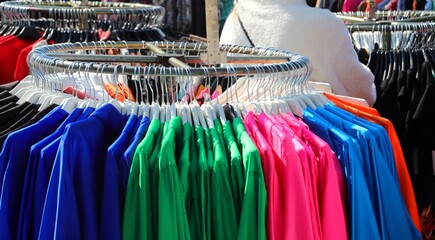 Obraz premium colored clothes hanging on the hangers in a trendy clothing stall of the outdoor market
