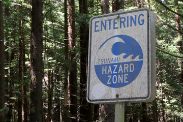 Closeup shot of a tsunami hazard zone sign against green trees