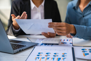Two business people sit down to analyze financial data from earnings graphs showing the company's earnings to be presented at a meeting.