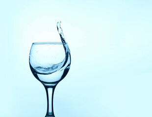 a glass of clean water with a splash on a light background with copy space