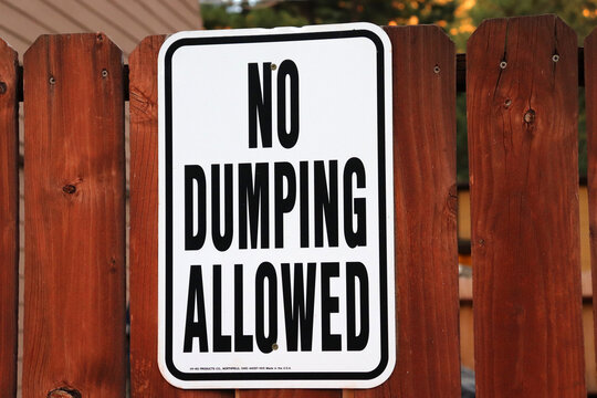 Closeup shot of a no dumping allowed sign on a wooden fence