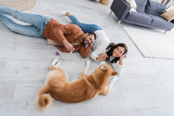 Fototapeta premium young couple lying of floor with akita inu dog.