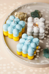 Two patriotic bubble candles - half blue, half yellow on beige colored seamless surface with starry light shadows