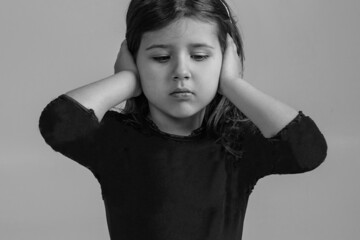 The little girl covered her ears with her hands and does not want to listen to anyone. Portrait of...