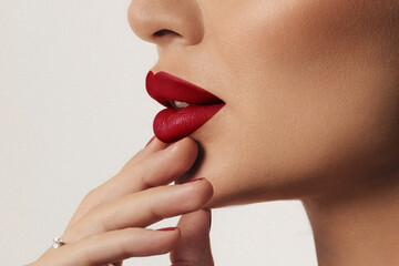 Close up side view of beautiful woman's lips with red lipstick and perfect shiny skin. Cosmetology, pharmacy or fashion makeup concept. Filmed in a beauty studio. A passionate kiss