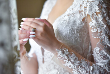 Bride trying on a wedding ring by the window