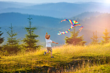 Little happy child boy play run with kite. Amazing mountain landscape in Alps at sunset with...