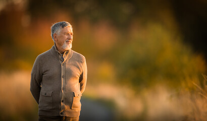 Portrait of handsome senior man in the autumn outdoors. Active senioor enjoying his retirement in...