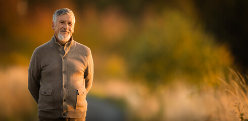 Portrait of handsome senior man in the autumn outdoors. Active senioor enjoying his retirement in...
