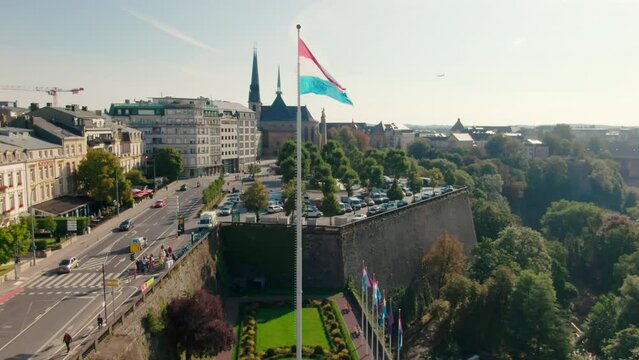Establishing Aerial shot of Luxembourg Cityscape Panorama with Landmark Skyline and National Flag Waving on Wind. Tourism, Travel or Urban b-roll Background. 4K drone zoom in shot