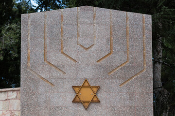 A menorah or Jewish candelabra and Jewish star of David adorn a memorial stone in the Mt. Herzl...