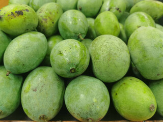 bunch of fresh green mango at a grocery store. Many mangoes are on the table for sale in markets. pile of mangoes for sale in the supermarket