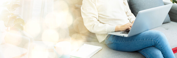 business woman Asian teenage girl sitting on sofa drinking coffee and using laptop inside the house The concept business finance working from home online shopping internet web banner with copy space 
