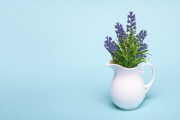 lilac flowers in a jug on a blue background with space for text