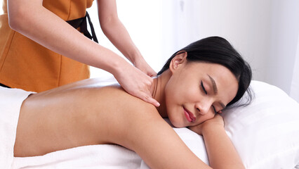 Obraz na płótnie Canvas Beautiful young Asian woman enjoying massage in spa salon