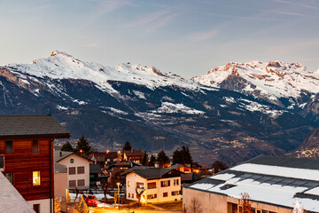 Sunset, nightfall in the swiss alps with mountains in the background and light from the houses, lot of snow, Nendaz, Switzerland