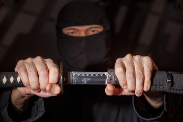 Ninja ready to fight, holding a Japanese sword. Photo of a warrior dressed in black clothes and...