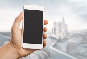 Human holds a smart phone in front of the city.