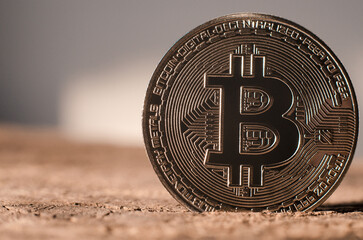 A golden bitcoin coin stands on a brown surface. World cryptocurrency
